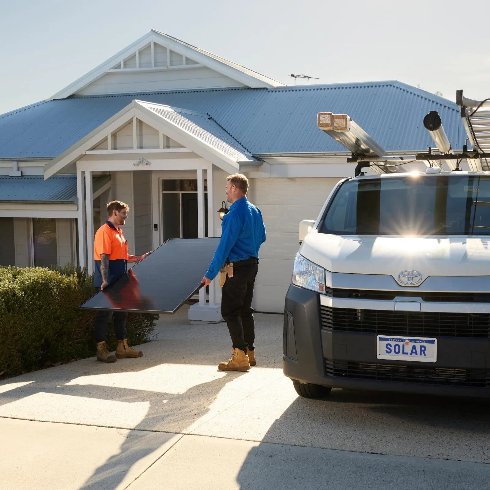 Solar installers carrying a panel beside a PSW Energy van