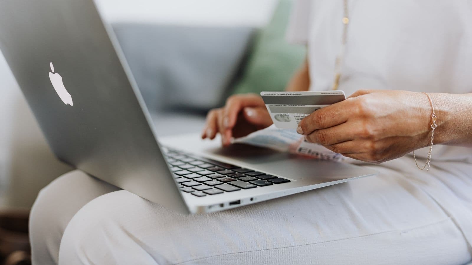 Person holding a payment card while using a laptop.