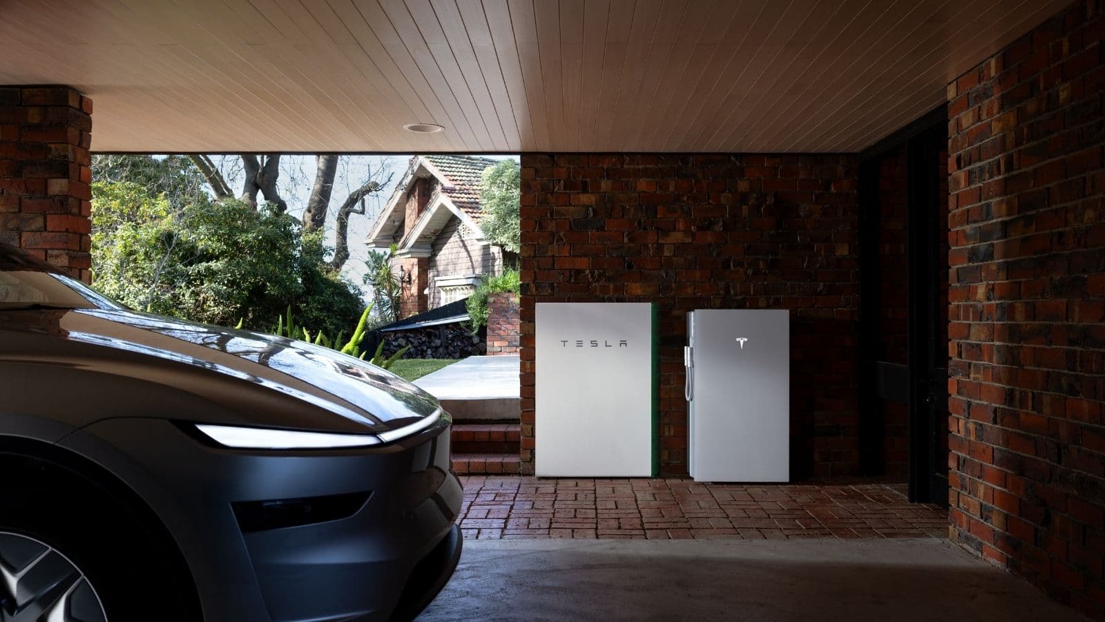 Tesla Powerwall 2 and Powerwall 3 batteries side by side against a brick wall, with an electric car in the foreground.