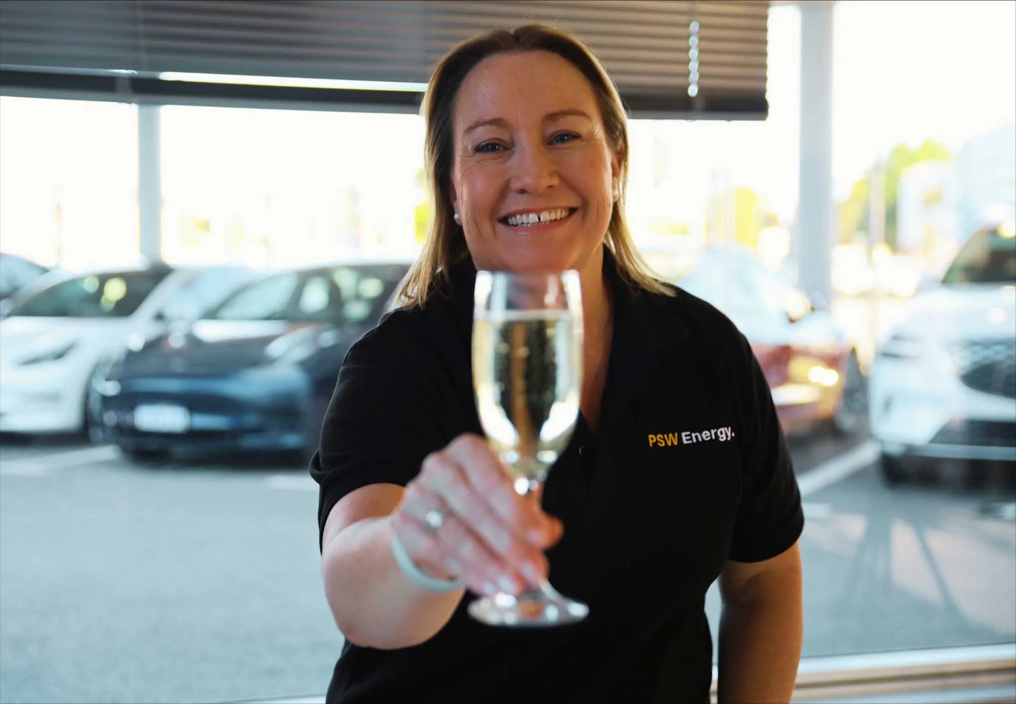 Kate Rutherford holding a glass of champagne for the Tesla Energy Performance Excellence Award
