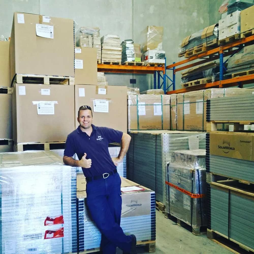 Derek McKercher standing among stacked solar panels in the early warehouse